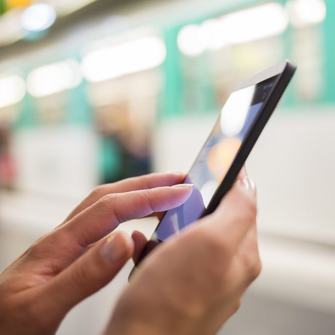 Manos de mujer usando su celular en el metro
