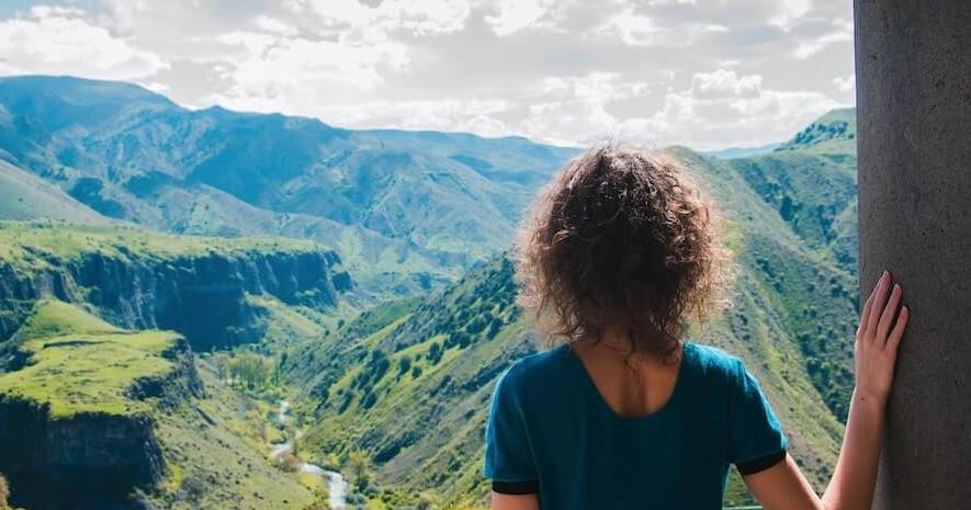 Mujer haciendo ecoturismo y mirando el horizonte lleno de montañas verdes