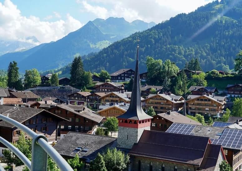Vista de casas traditionales en Gstaad, Suiza con unas montañas al fondo