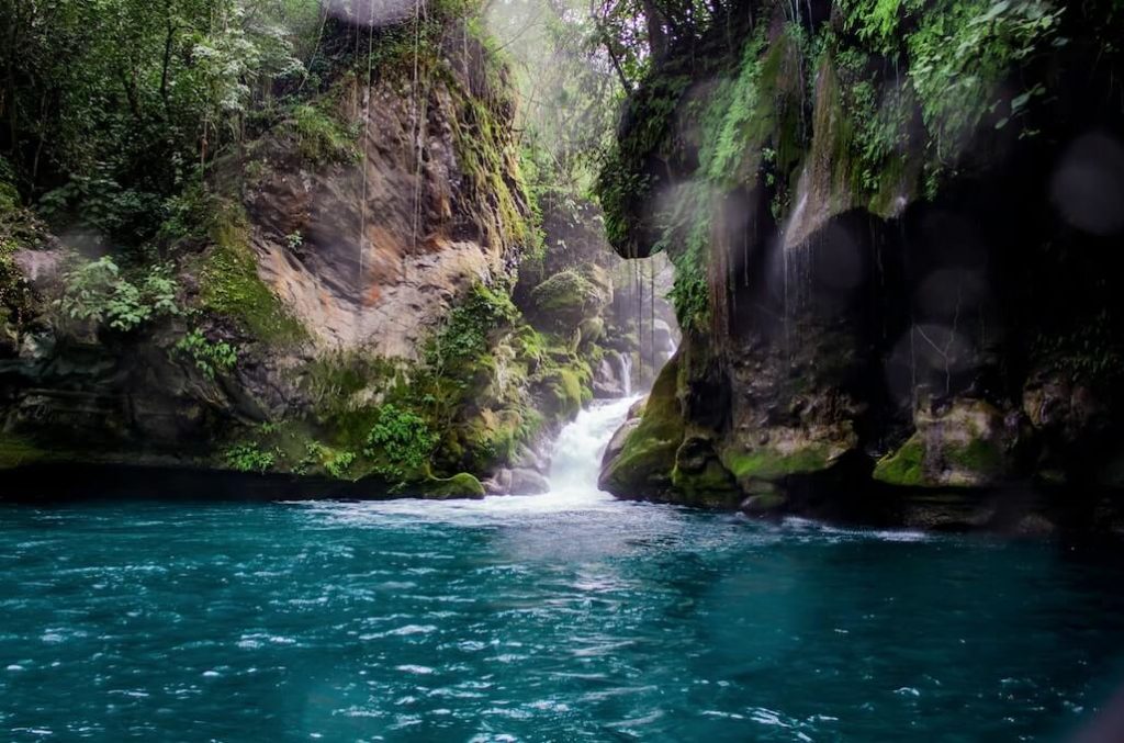 Río de agua turquesa con una cascada entre piedras con musgo y vegetación verde en Puente de Dios, Tamasopo, San Luis Potosi