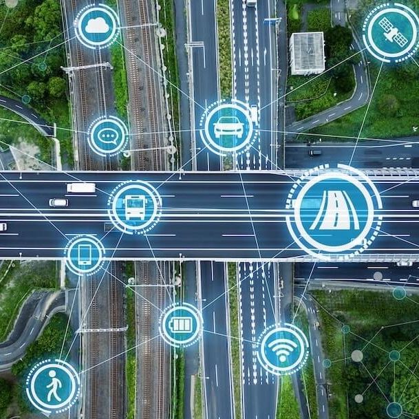 Vista aerea de una carretera inteligente con iconos de puntos de recarga, autobuses electricos, semaforos inteligentes y wi-fi