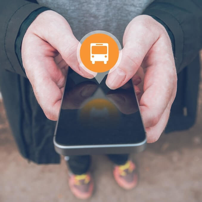 Hombre usando una plataforma de movilidad en su celular con el icono de un autobus en la pantalla